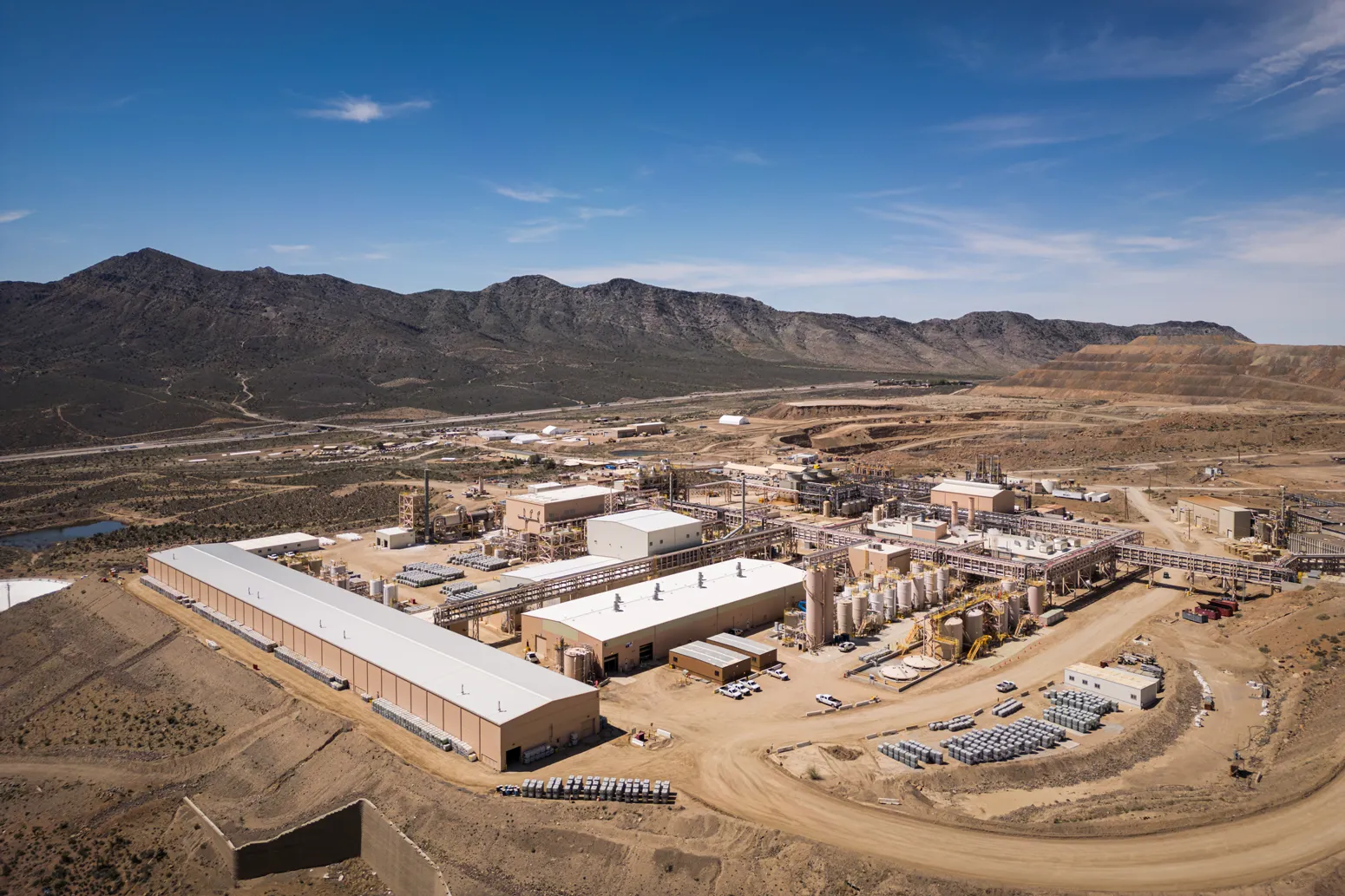 Aerial photograph of the Mountain Pass rare-earth mine and processing facility in California, with the open pit and the processing plant buildings and tank farms beside it.
